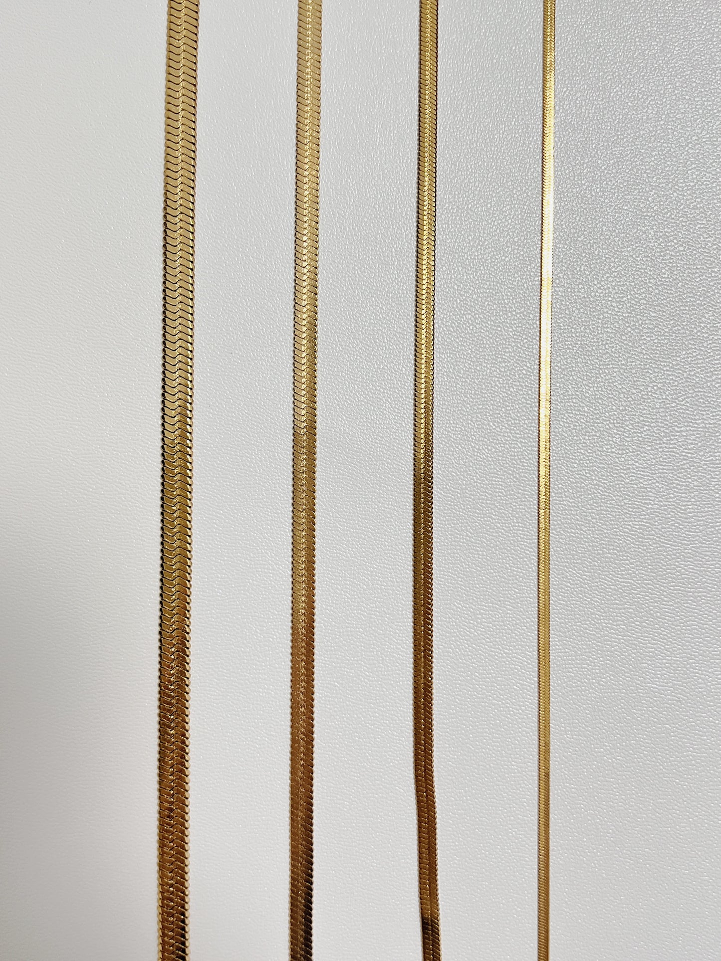 Thick and thin flat snake chain necklaces highlighting the flexible unyielding stainless steel core architecture