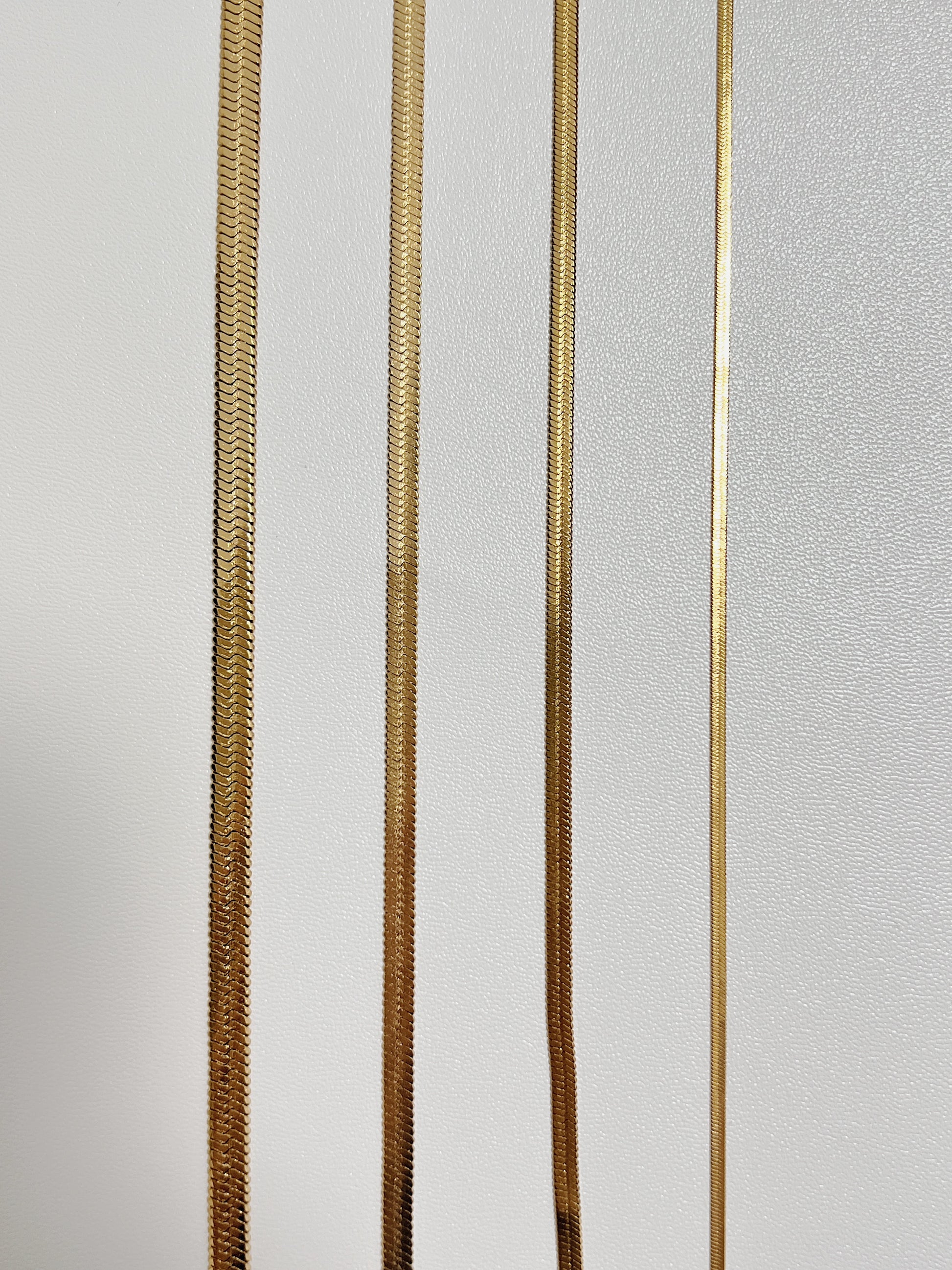 Thick and thin flat snake chain necklaces highlighting the flexible unyielding stainless steel core architecture