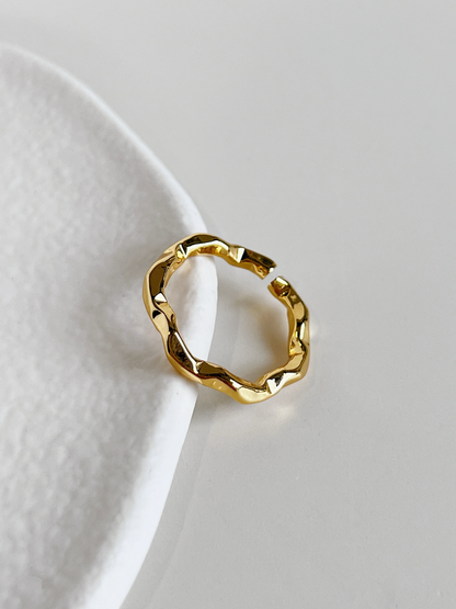 Close-up view of the soft organic wave curves on the dainty gold band