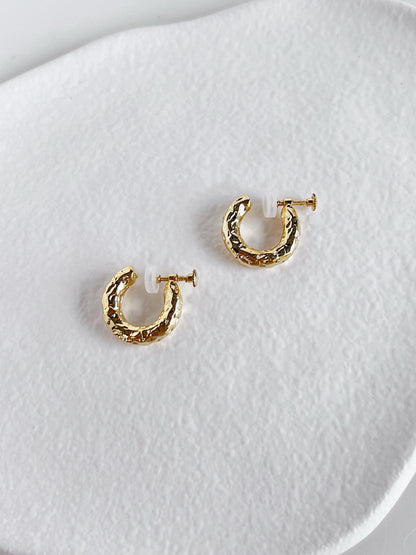 Editorial arrangement of the Gigi hammered clip-on hoops resting on an ivory dish for capsule wardrobe jewelry lovers.