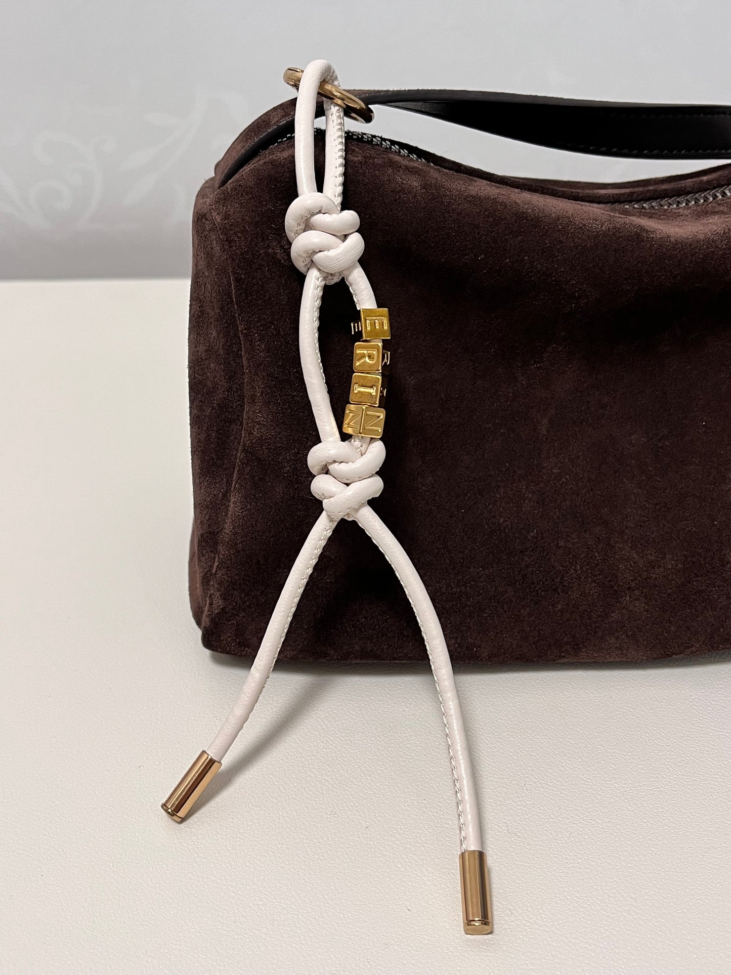 Close-up of gold initial beads on leather charm.