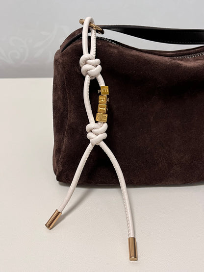 Close-up of gold initial beads on leather charm.