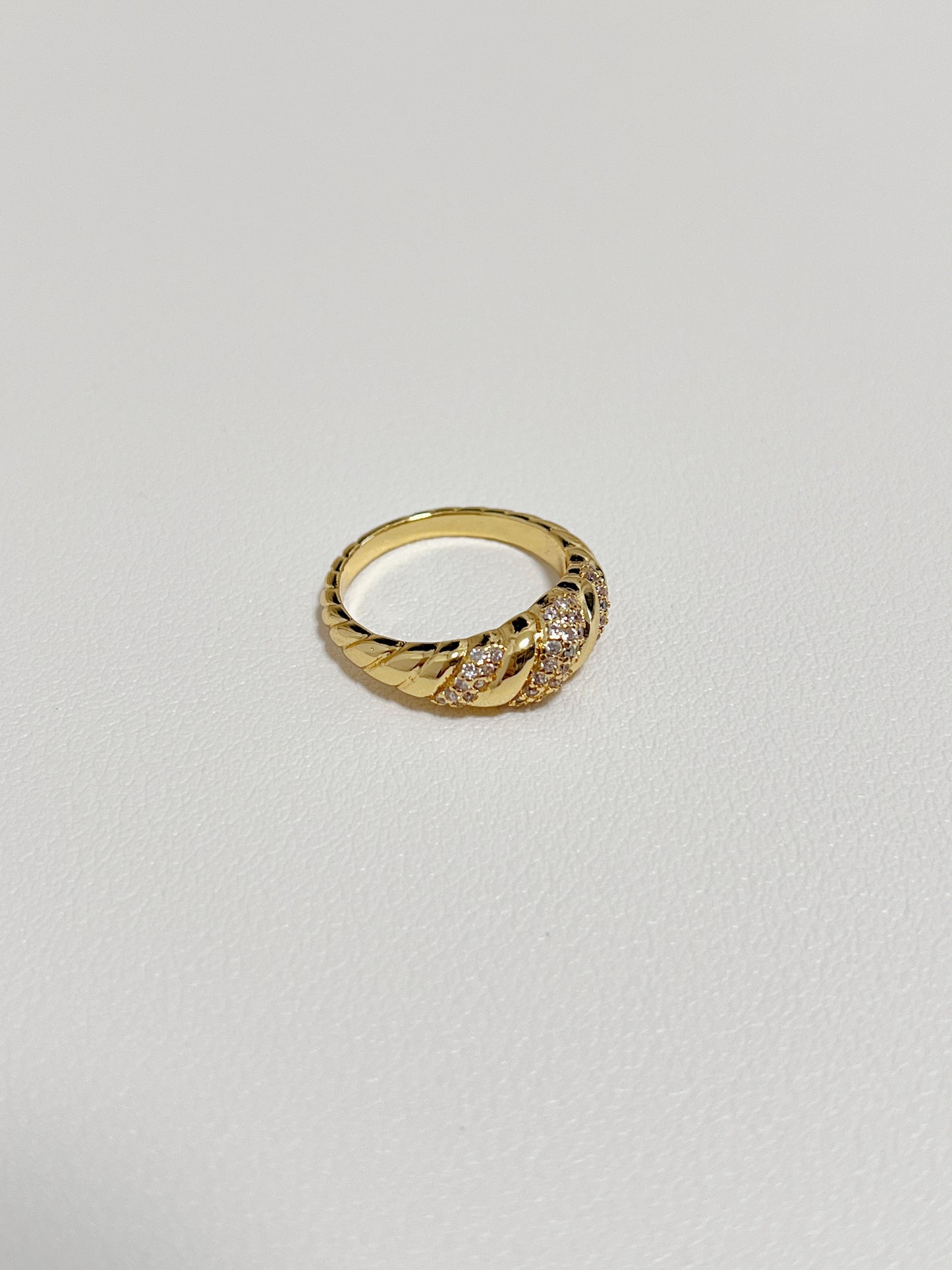 Claudia gold croissant ring displayed on a modern, minimalist white leather surface.