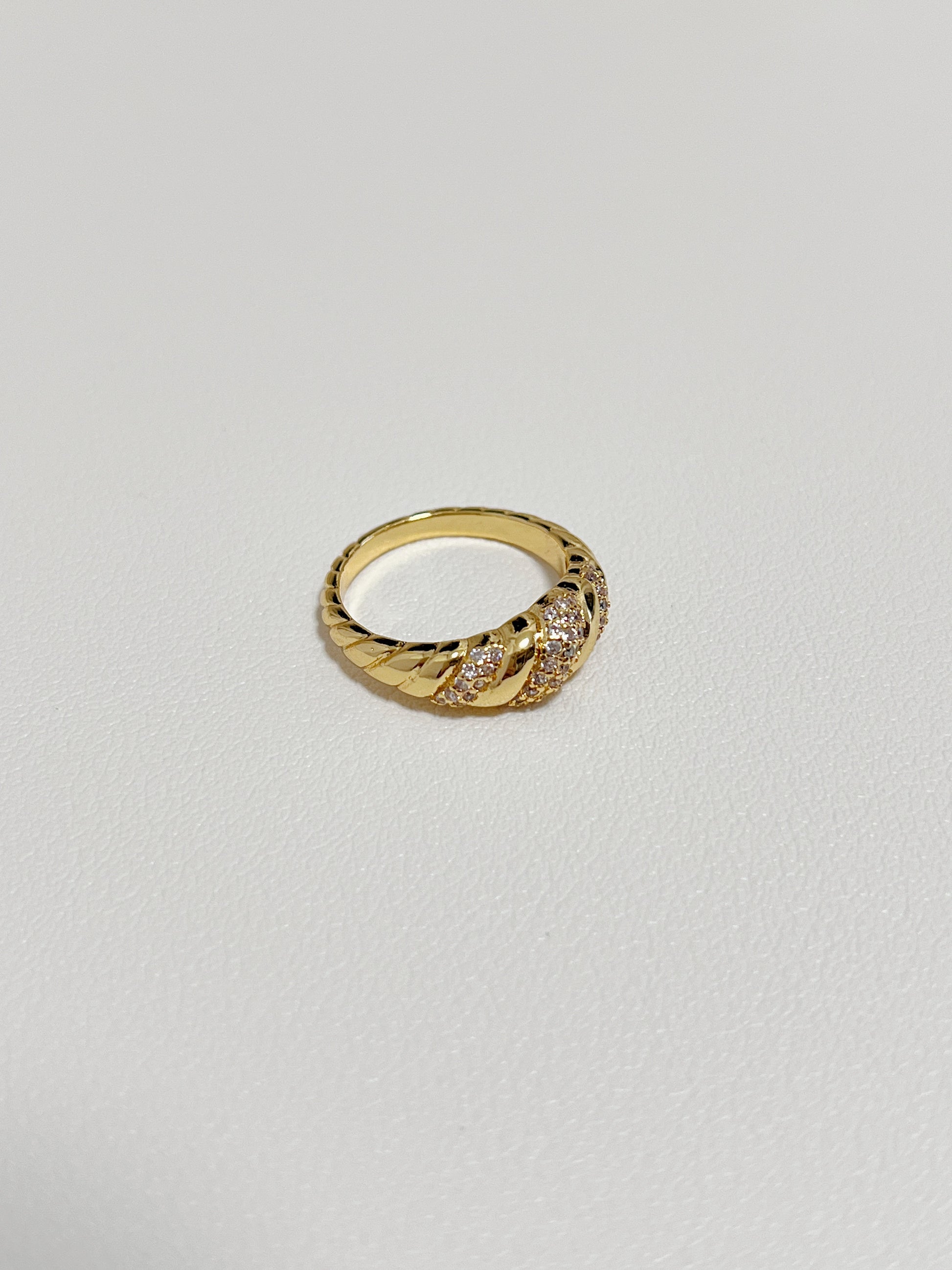 Claudia gold croissant ring displayed on a modern, minimalist white leather surface.
