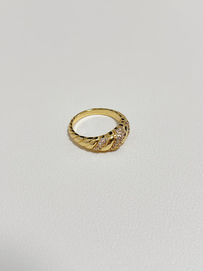 Claudia gold croissant ring displayed on a modern, minimalist white leather surface.