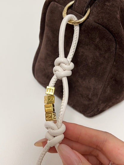 White leather initial charm with gold beads.