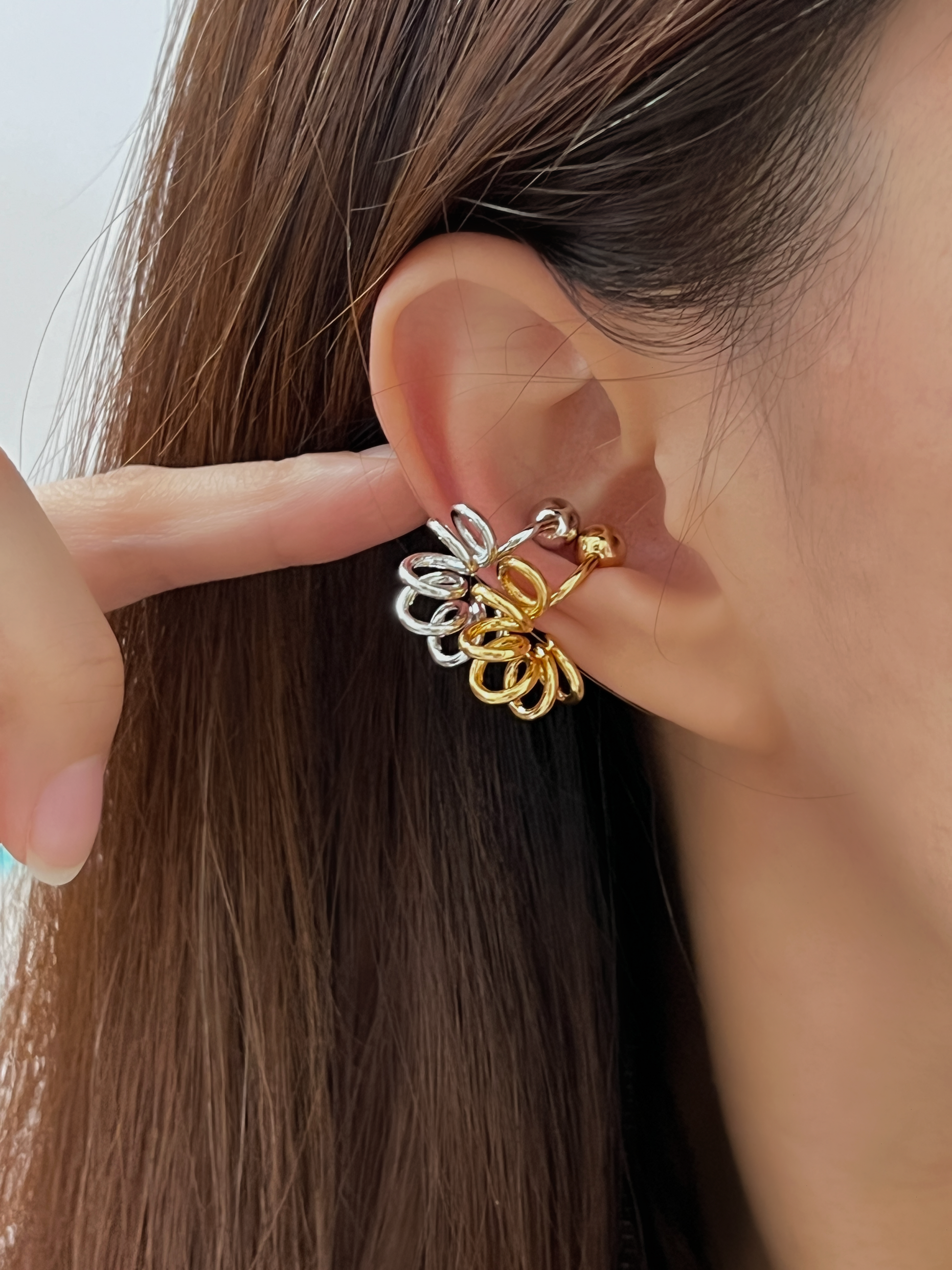 Close-up of model's ear with the gold and silver coil cuff for quiet luxury.