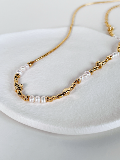 A close-up view highlighting the genuine freshwater pearls and 18k gold PVD coated snake chain of the Greta necklace on a white background.