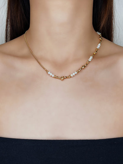 Editorial on-model view of Greta demi-fine necklace highlighting the asymmetrical blend of minimalist gold snake chain and fluid, baroque pearls styled for a modern luxury look.