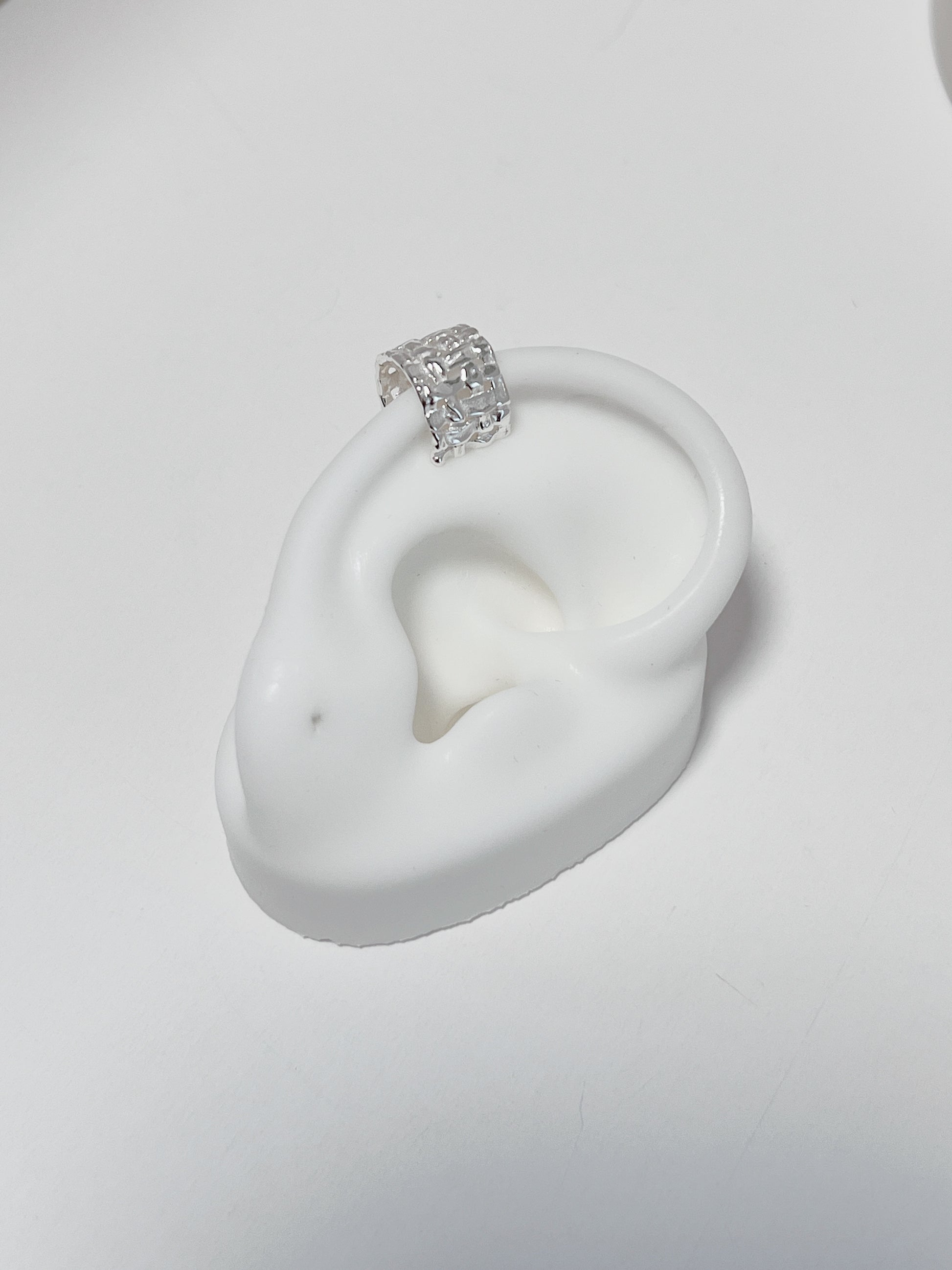 Natural light shot of the Carmela cuff on a white fake silicone ears showing the authentic, premium silver luster.