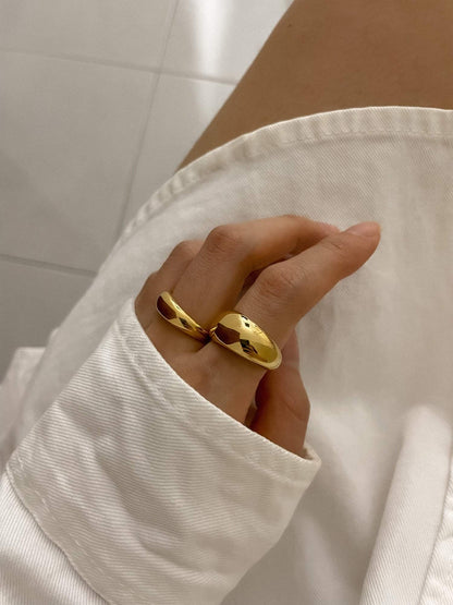 Hand model wearing thick Eloise gold dome ring on index finger and slim Eloise gold dome ring on middle finger