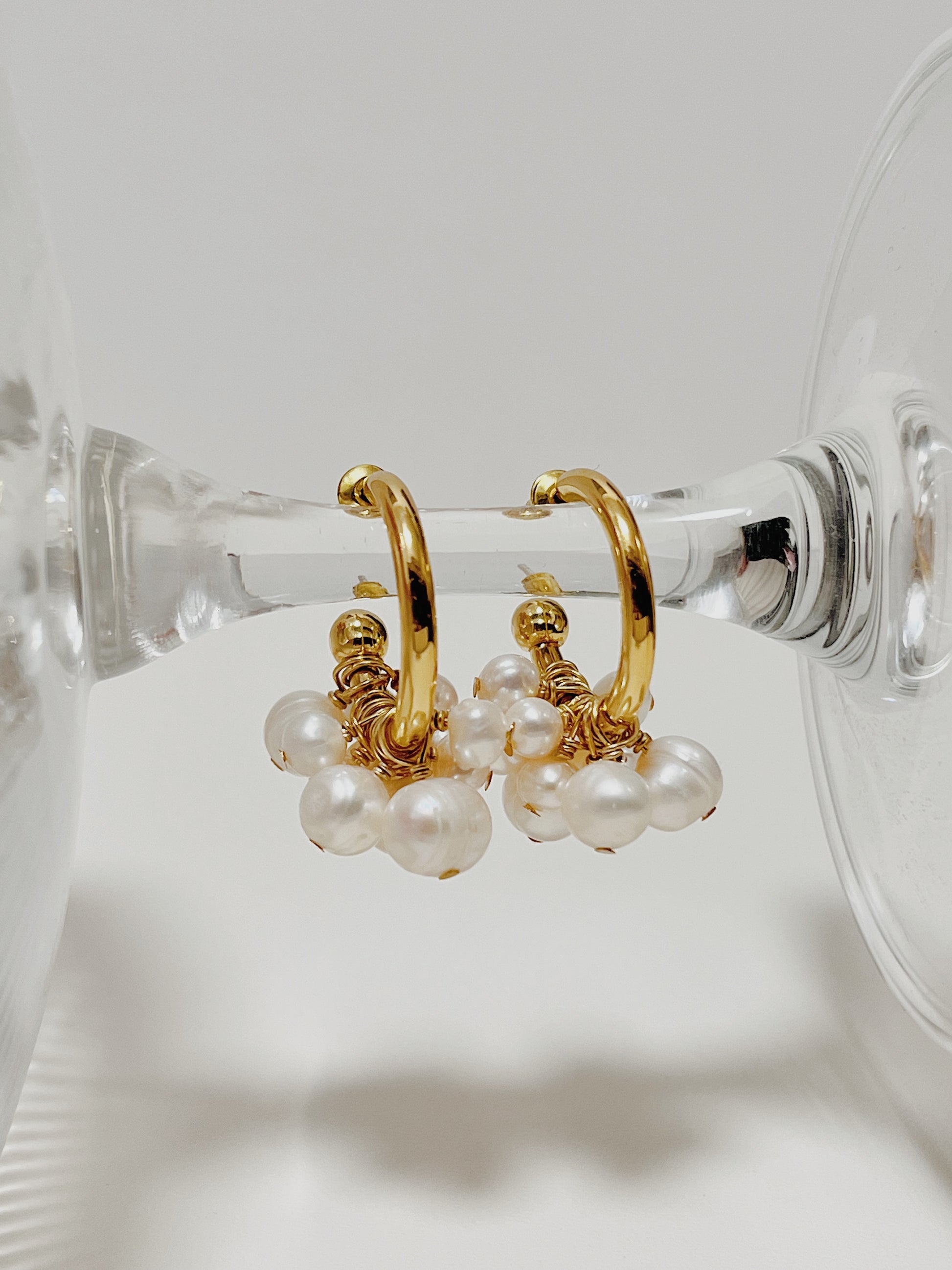 Macro detail of a single Freya cluster pearl hoop earring on a minimal backdrop, showcasing the hand-selected grade-A cultured pearl texture.