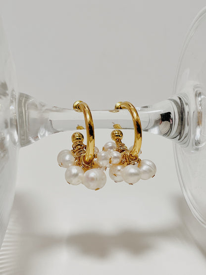 Macro detail of a single Freya cluster pearl hoop earring on a minimal backdrop, showcasing the hand-selected grade-A cultured pearl texture.