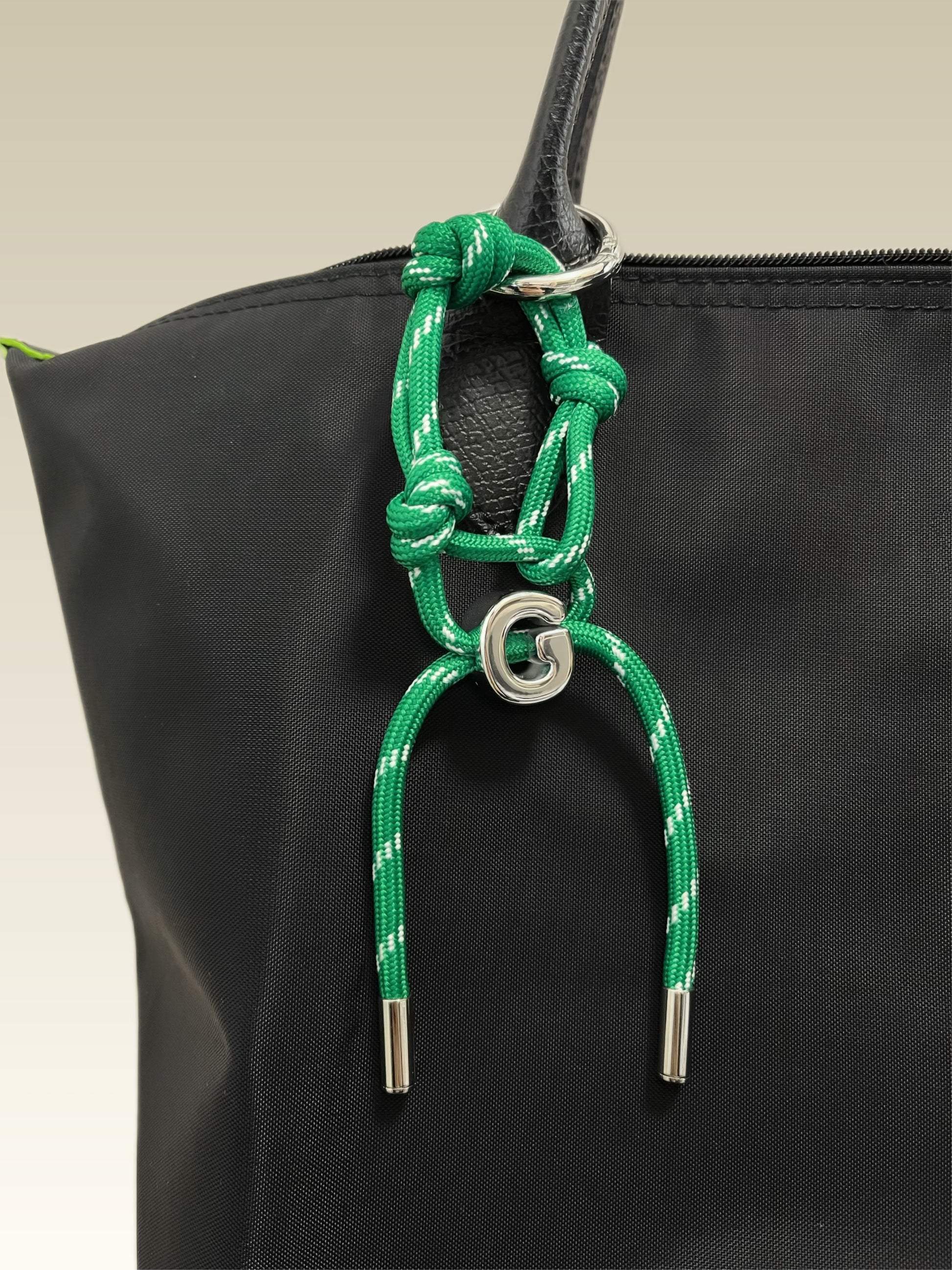 Studio product shot of a kelly green personalized large letter bag charm with a silver G initial monogram block
