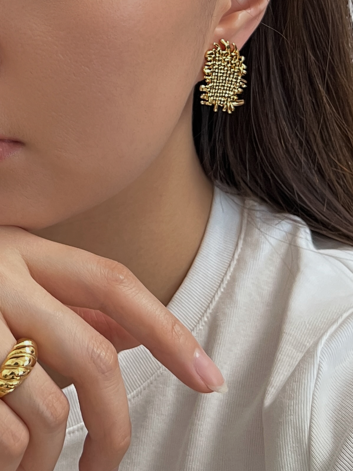 Model wearing Hazel gold statement clip-on earrings styled with white t-shirt