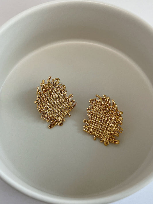 Pair of 18K gold plated Hazel woven textured clip-on earrings on neutral background