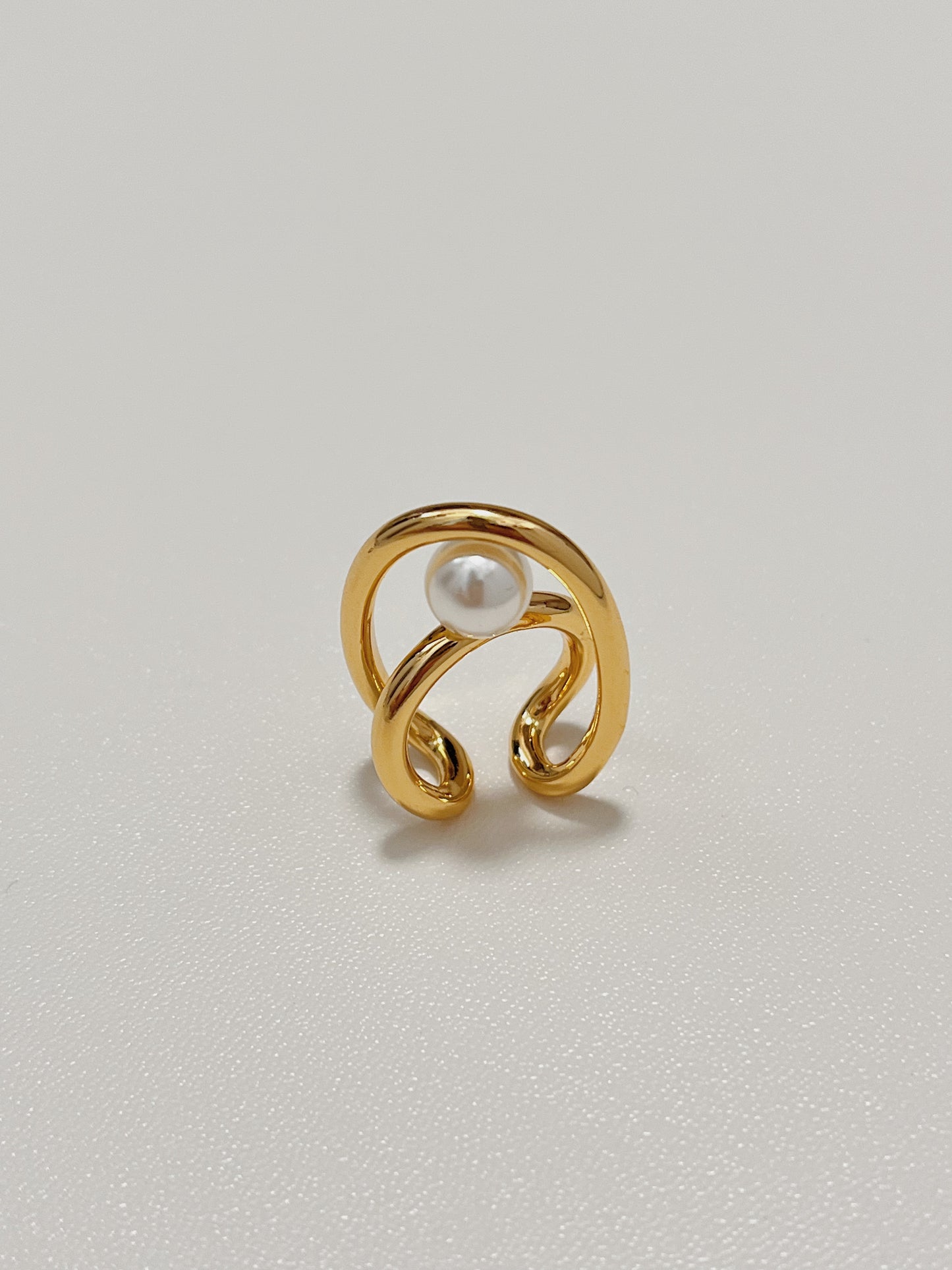 Overhead close-up of the gold Karolina statement ear jewelry, emphasizing the pristine, unblemished surface of the high-luster round pearls nestled within the sleek metal frames.