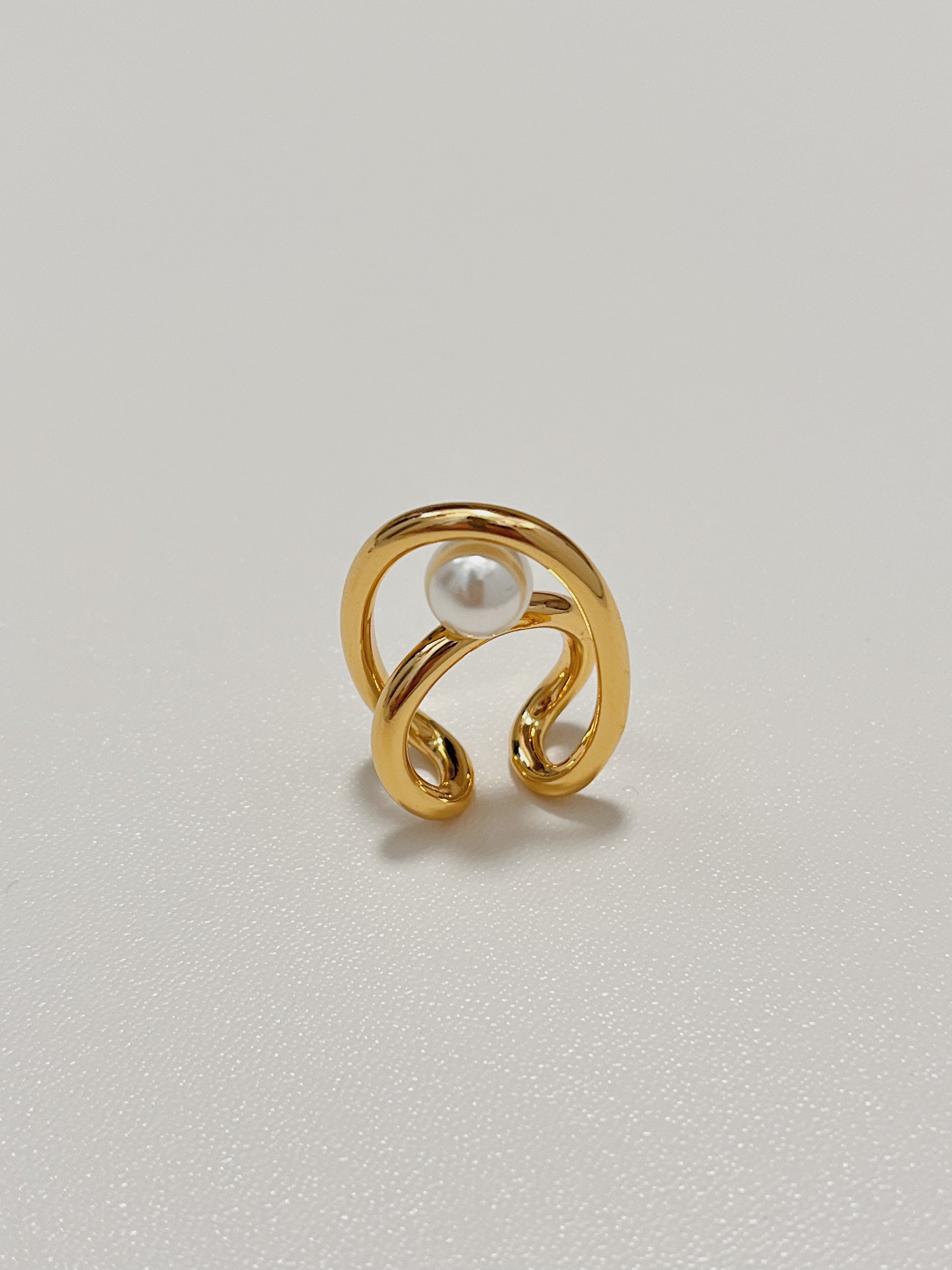 Overhead close-up of the gold Karolina statement ear jewelry, emphasizing the pristine, unblemished surface of the high-luster round pearls nestled within the sleek metal frames.