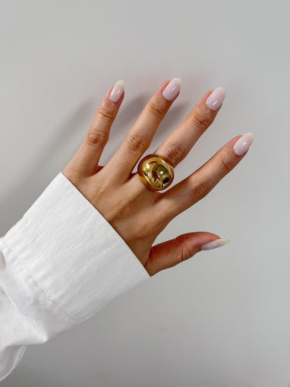 High-mirror gold sculptural ring catching light on model's finger