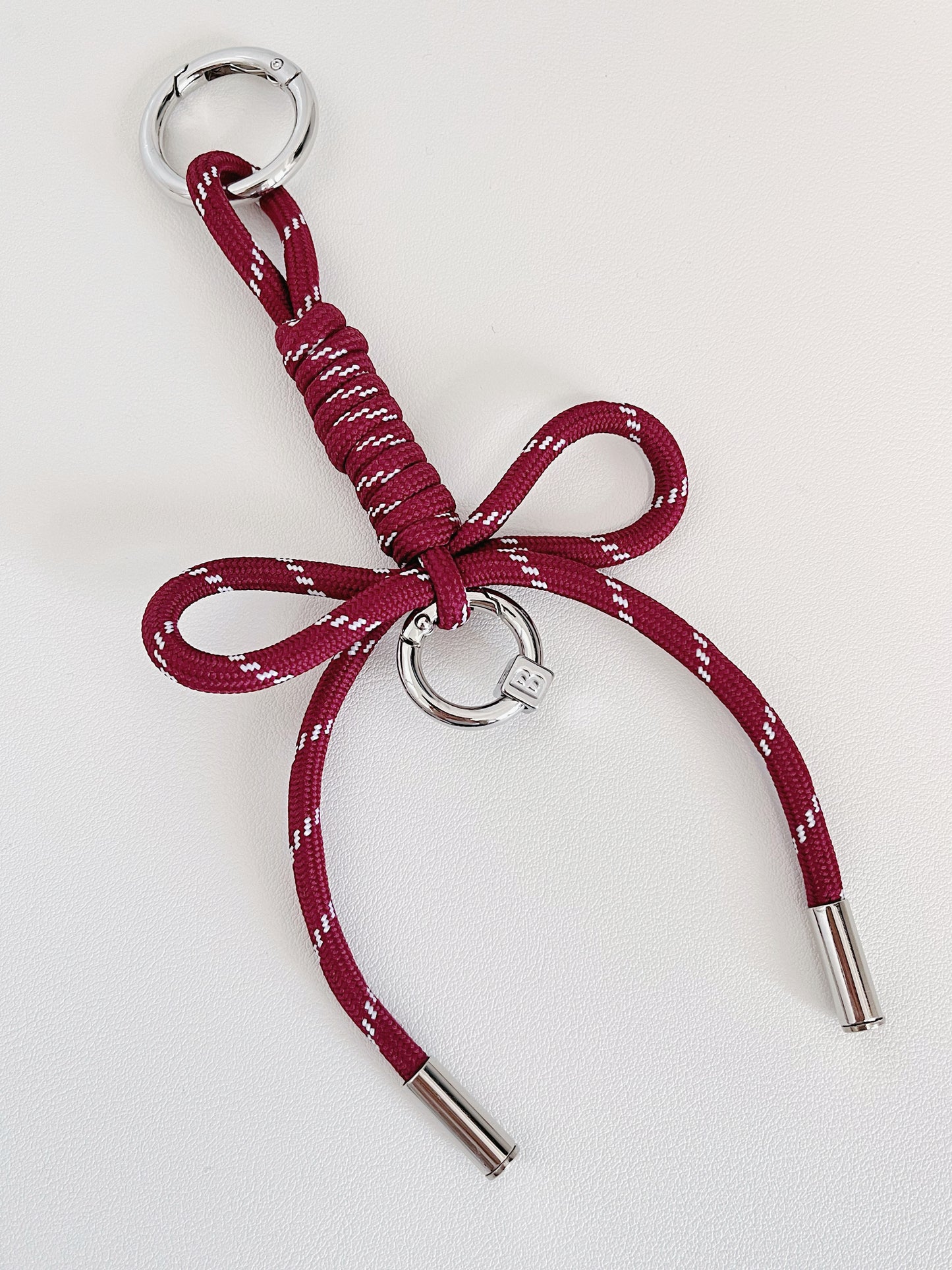 Symmetrical flat lay of a custom cord bow keyring showcasing secure dual spring loaded carabiner clips