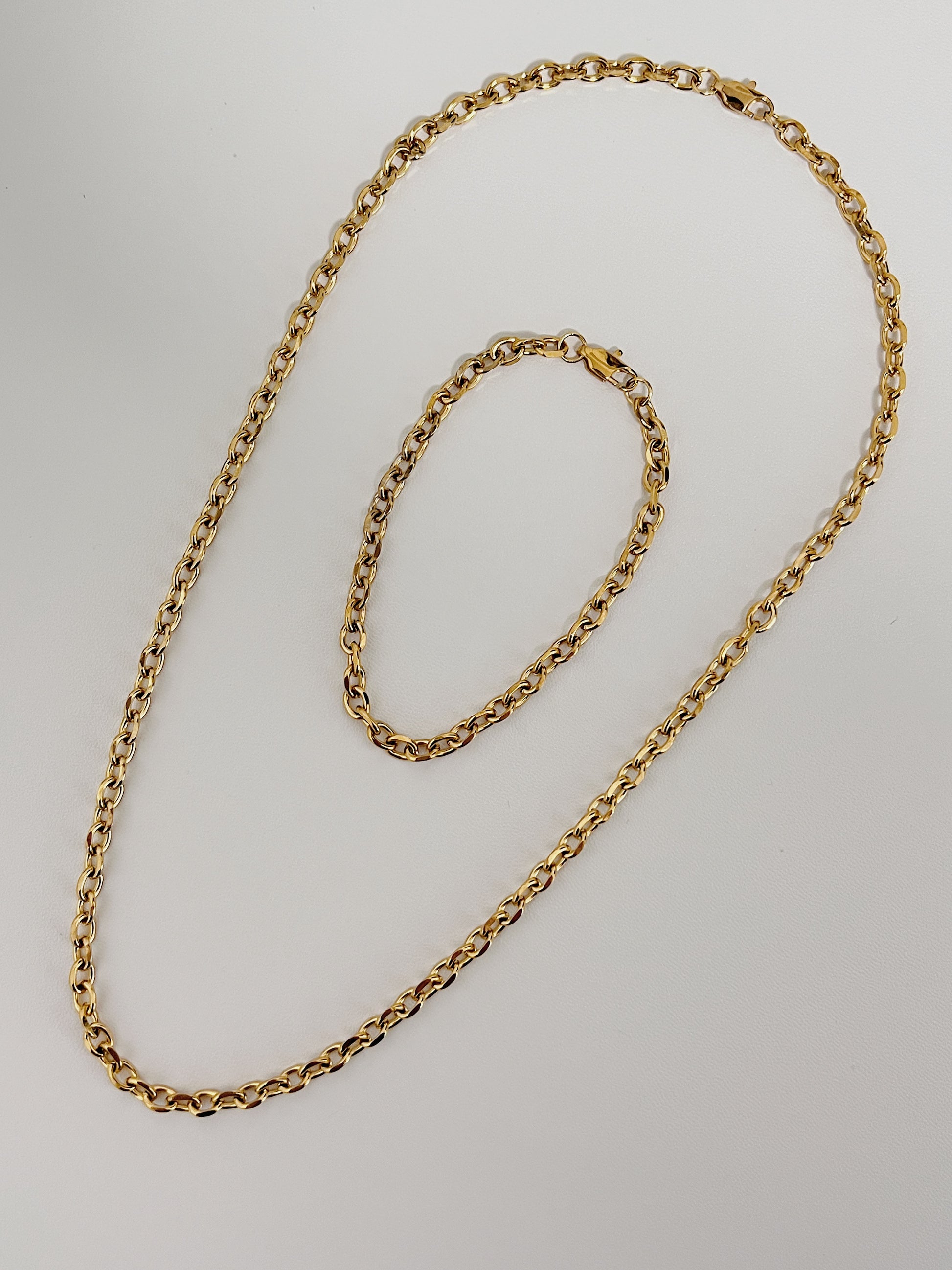 Premium demi fine jewelry catalog display focusing on the structural core alignment of a gold chain necklace and bracelet