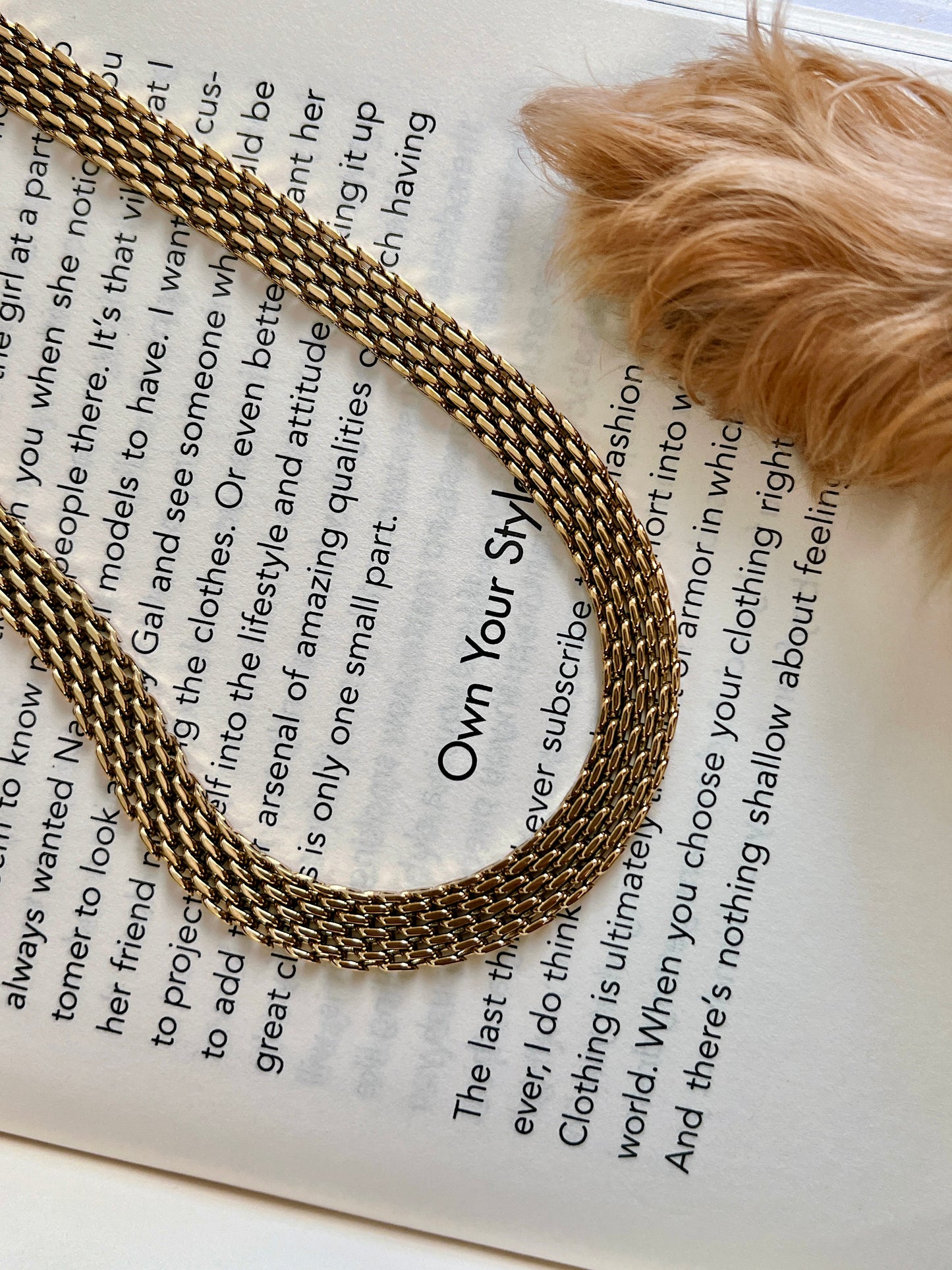 High luster gold mesh jewelry resting on a clean white surface capturing soft ambient light reflections