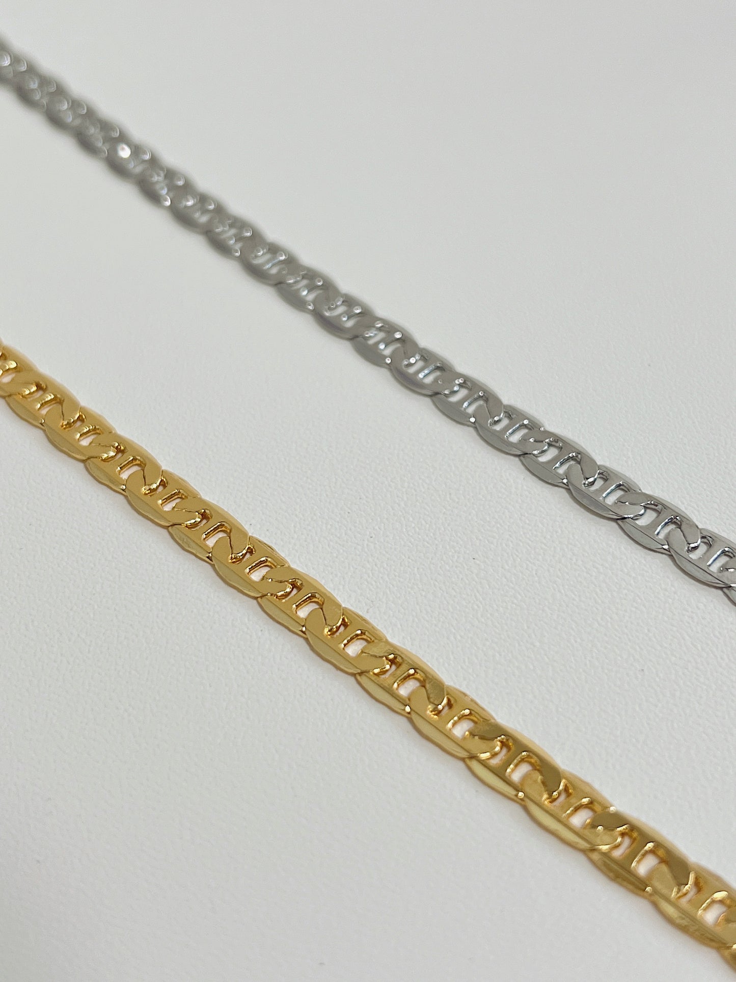 Close up perspective of the highly reflective flat-milled anchor links on an 18k gold plated mariner necklace