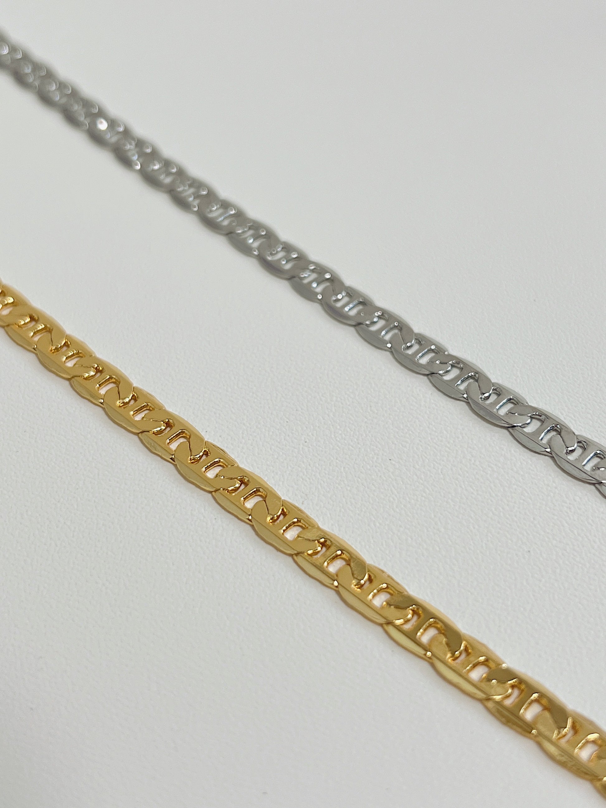 Close up perspective of the highly reflective flat-milled anchor links on an 18k gold plated mariner necklace