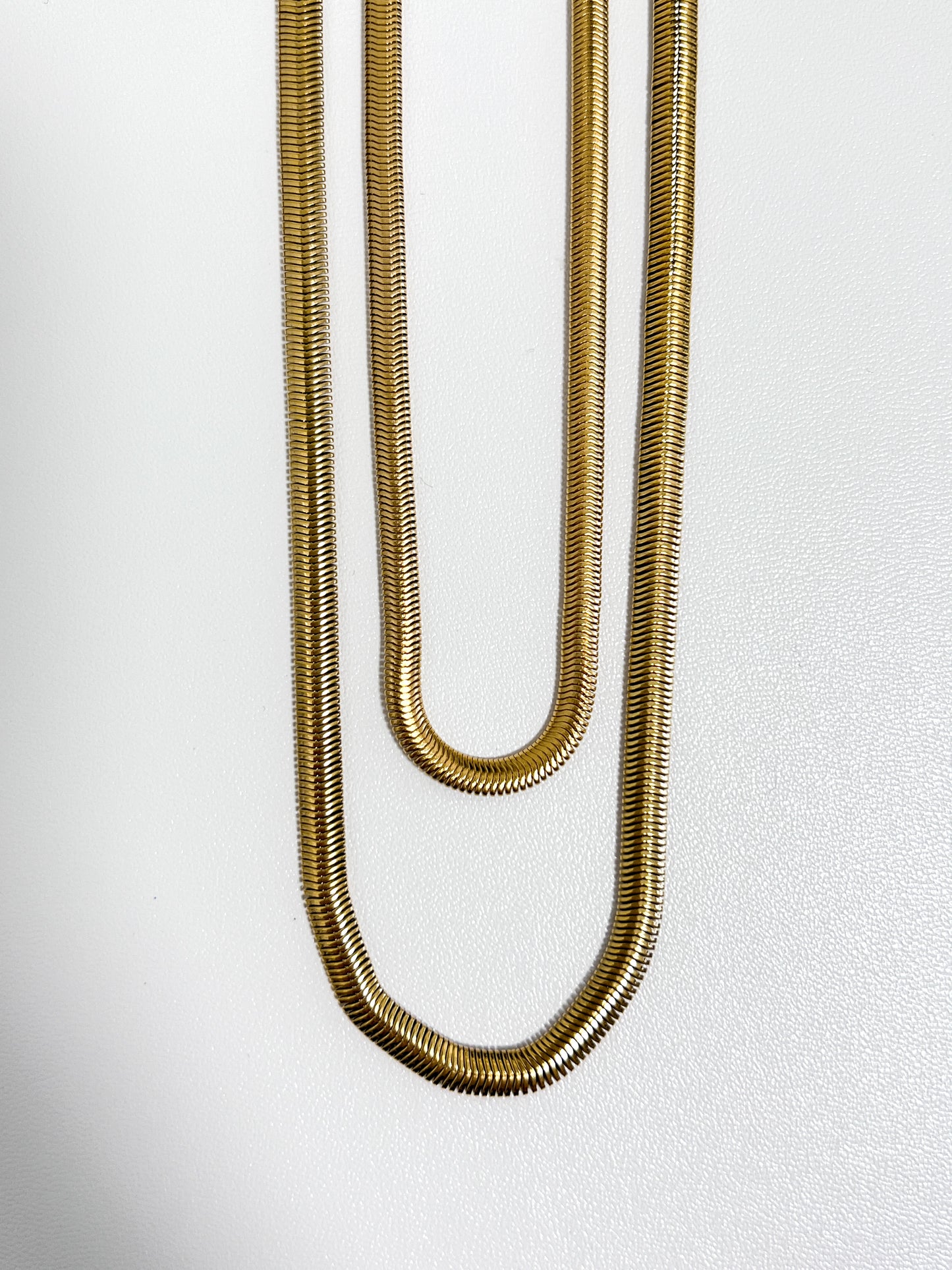 Close up perspective of the highly reflective mirrored scales on an 18k gold pvd snake chain necklace