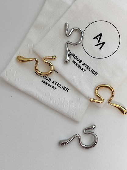 Side-by-side comparison of gold and silver Tia cuffs on a minimalist pedestal.