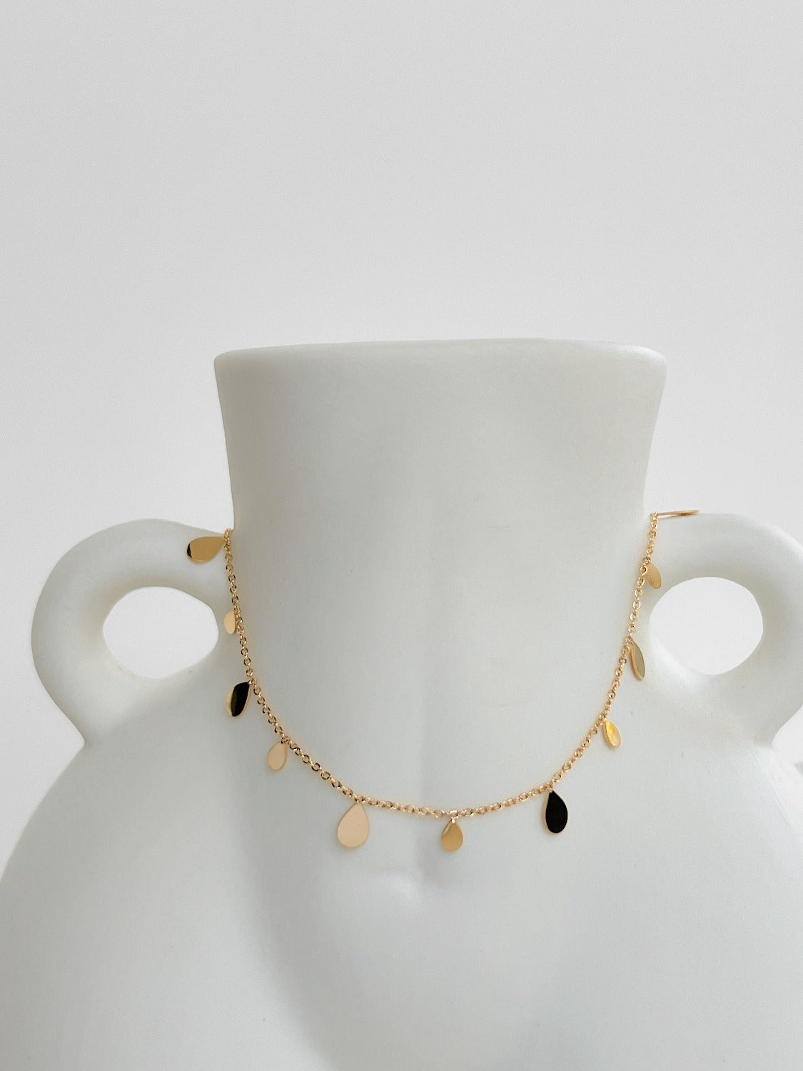 Contemporary luxury statement necklace displaying mirror polished golden droplet summer sun reflection