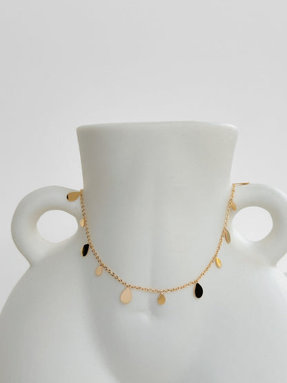 Contemporary luxury statement necklace displaying mirror polished golden droplet summer sun reflection