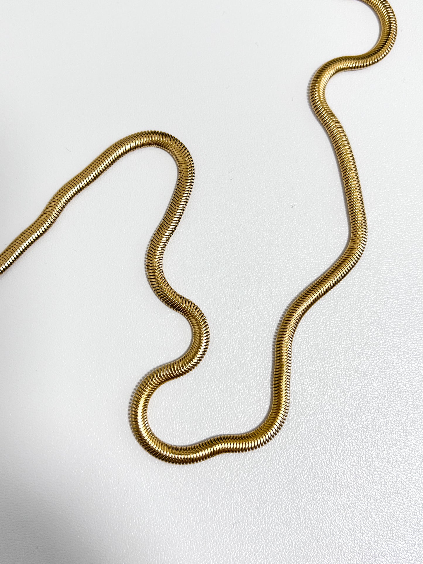 Bespoke studio product asset showing a thick gold liquid herringbone ribbon resting on a white background