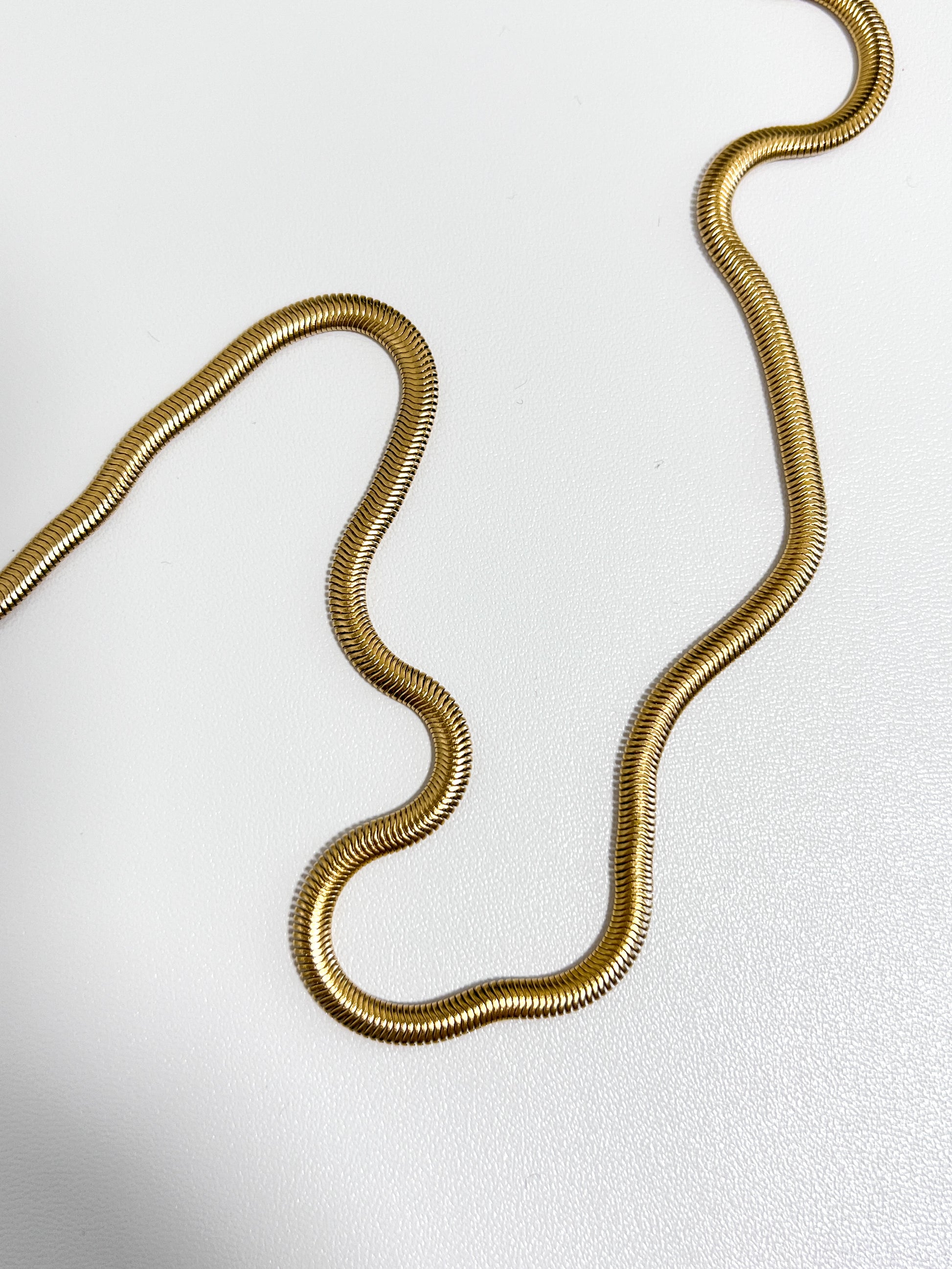 Bespoke studio product asset showing a thick gold liquid herringbone ribbon resting on a white background
