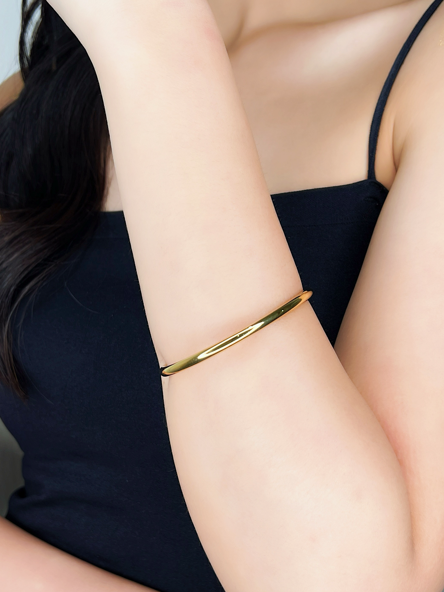 Side view detail of the Ines 18K gold PVD cuff bangle on-model, demonstrating how the open-cuff design drapes comfortably against the wrist.
