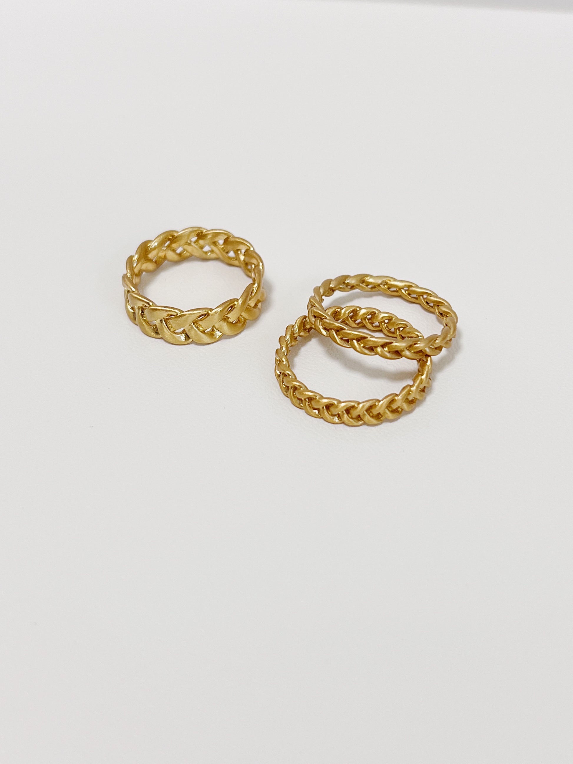Side-by-side view of matte 18k gold PVD Irene twisted rings in different width.