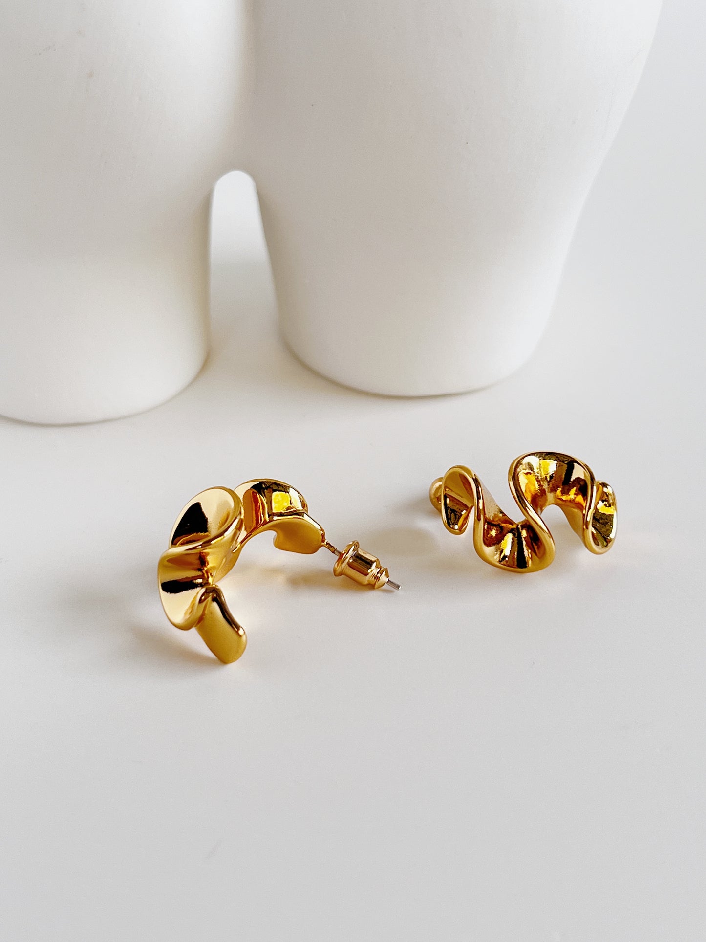 Close-up of the fluid wavy silhouette of Isla gold earrings