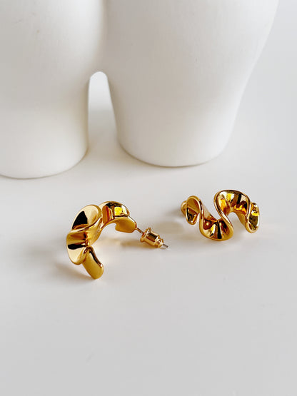 Close-up of the fluid wavy silhouette of Isla gold earrings