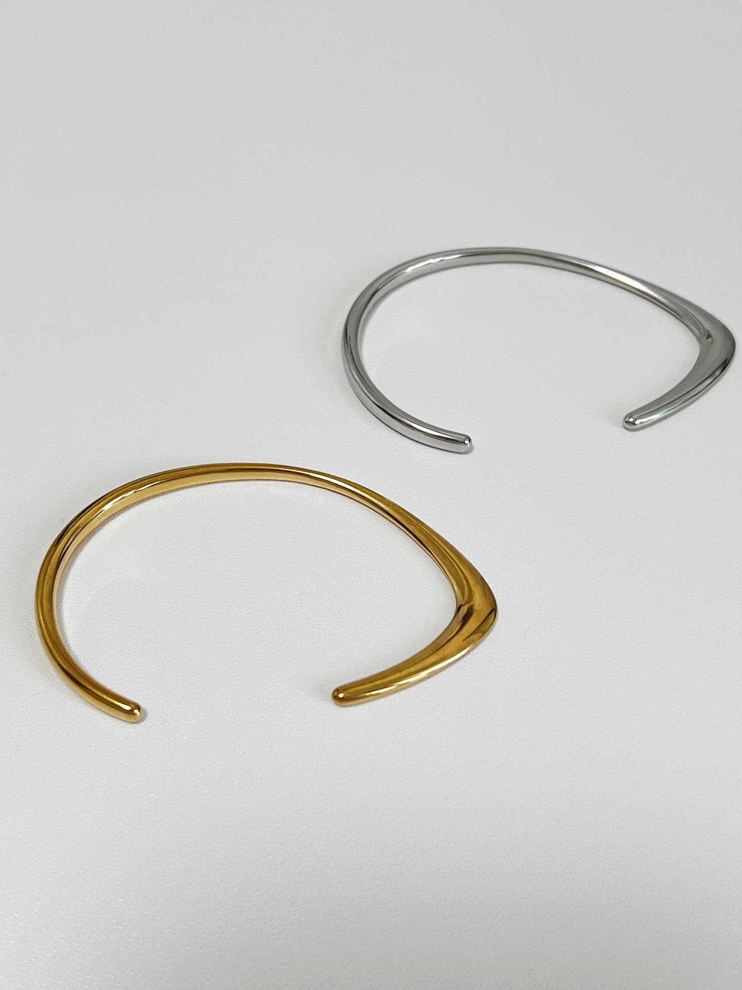 Macro perspective focusing on the sharp architectural ridge and high-mirror finish of the 18K gold PVD irregular dual-profile cuff layout.