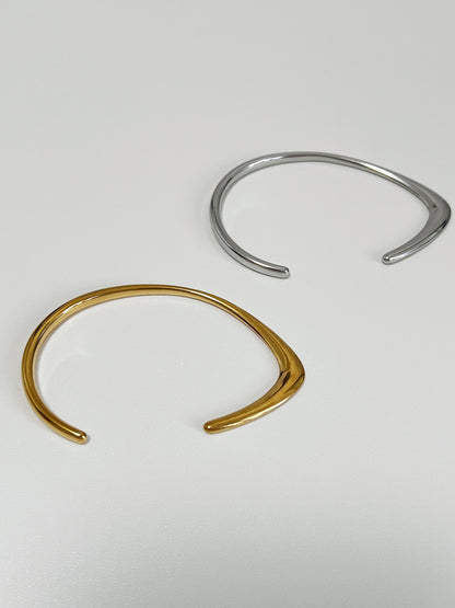 Macro perspective focusing on the sharp architectural ridge and high-mirror finish of the 18K gold PVD irregular dual-profile cuff layout.