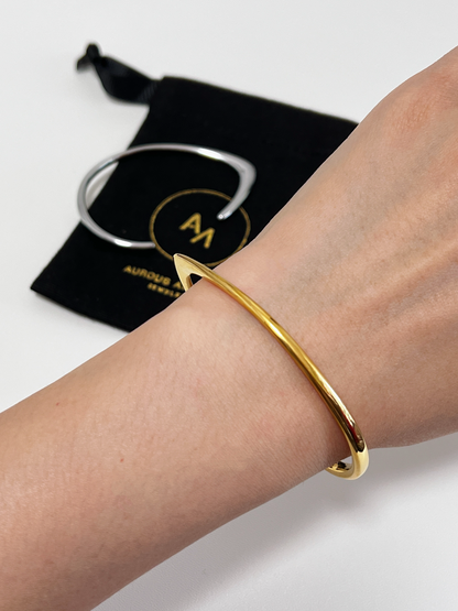 Close-up profile of a model wrist, styled with a gold Iva cuff and silver iva cuff at the background.