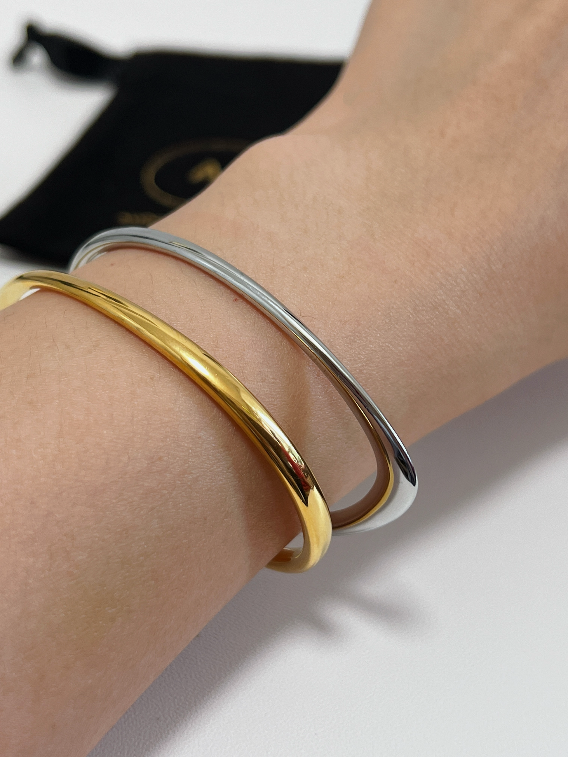 Side view showing the unique, varying width of the gold and silver  Iva sculptural cuff as it catches the light on a model's forearm.