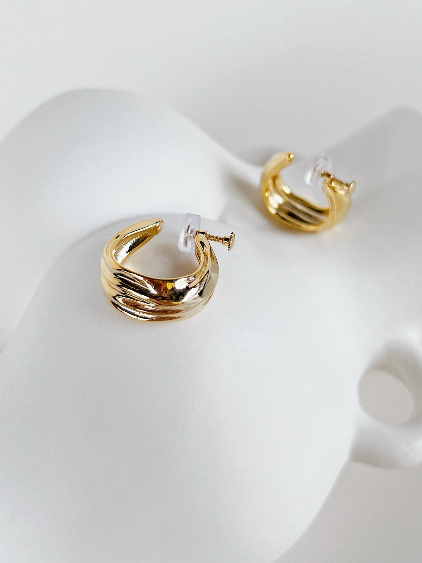 Close-up shot of adjustable threaded screw-back mechanism with clear silicone pad on gold clip-on hoop