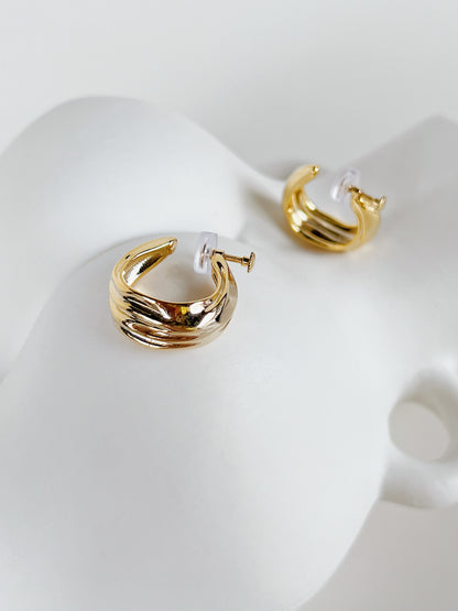 Close-up shot of adjustable threaded screw-back mechanism with clear silicone pad on gold clip-on hoop