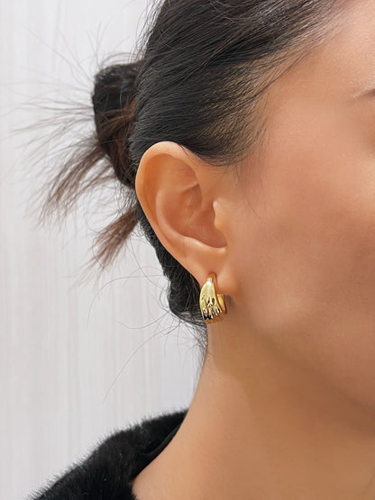 Model wearing Ivette gold clip-on hoops styled with a fur jacket