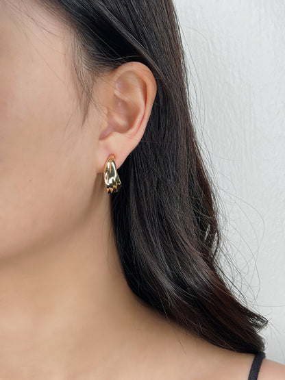 Model wearing Ivette gold clip-on hoops styled with a black tank top