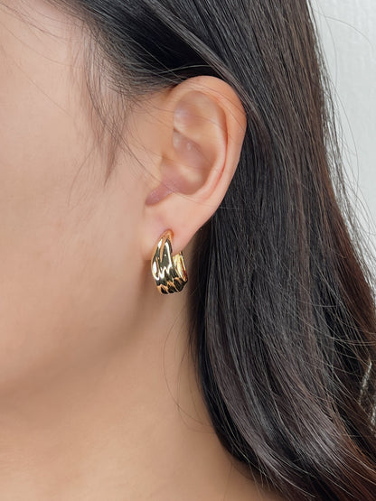 Close-up side profile of model wearing gold Ivette tiered molten clip-on hoop on unpierced earlobe