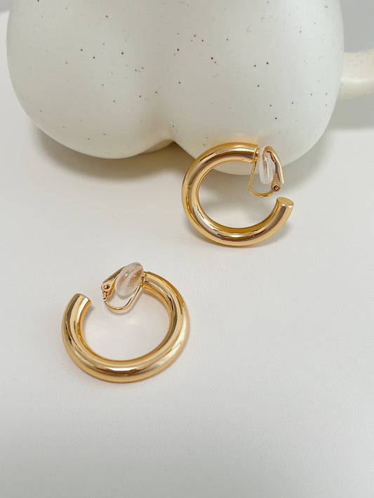 Macro studio photograph displaying the mirror-polished 18k gold plated surface and smooth tubular curves of the 30mm C-hoops.