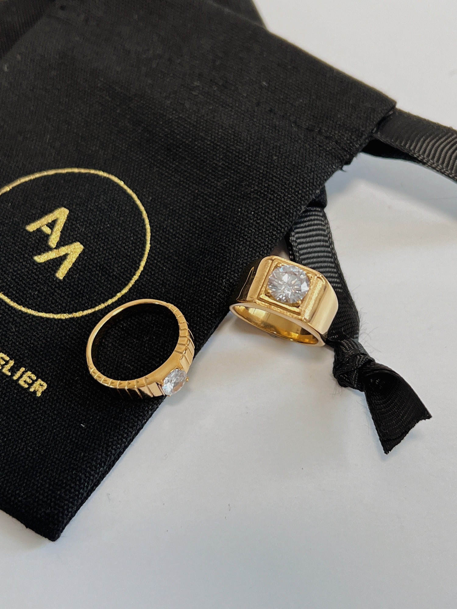 Kass gold rings resting on a black jewelry pouch.
