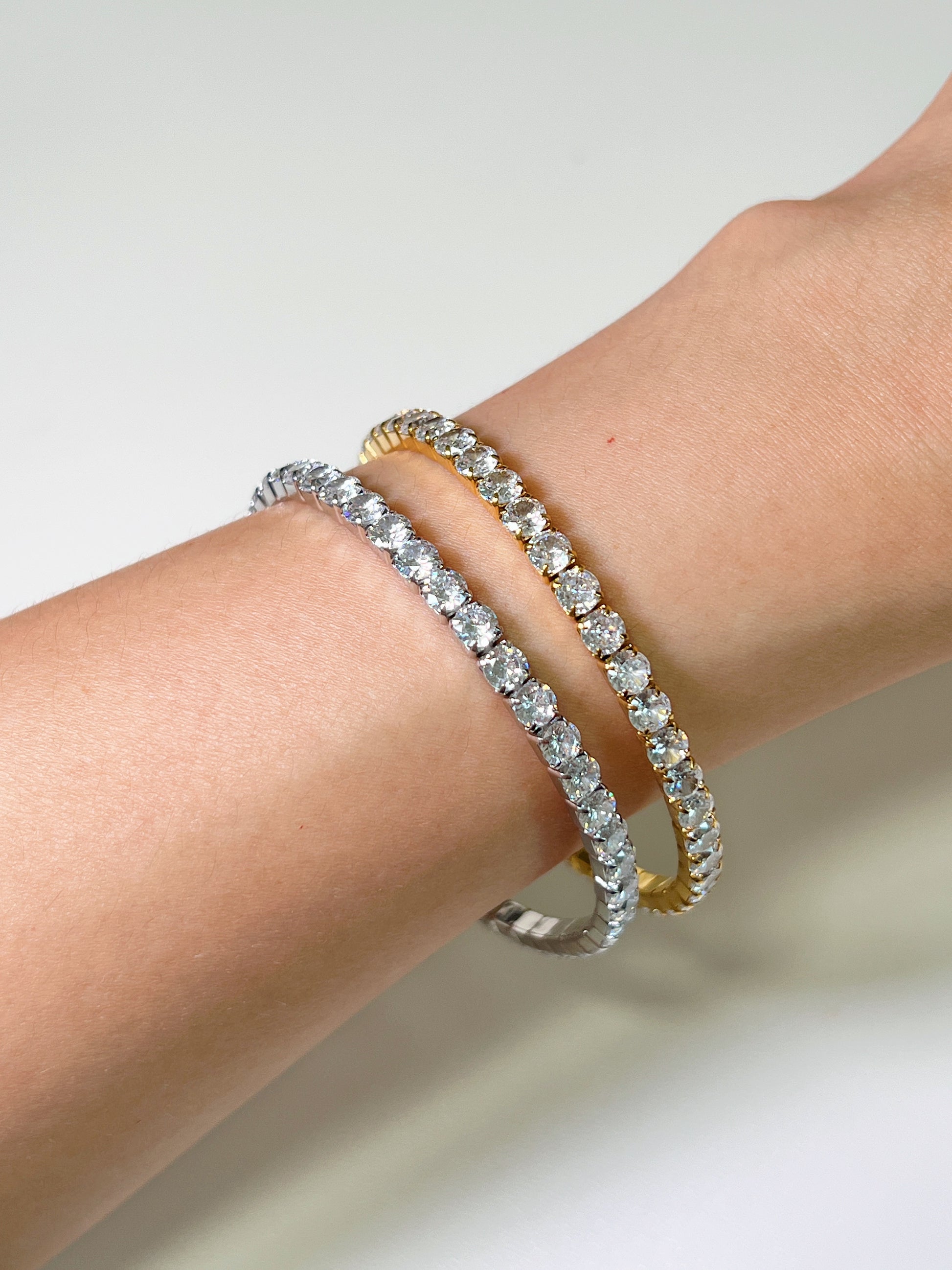 Detailed side profile view of 18K gold PVD and silver tone 4mm elastic tennis bracelets on an arm demonstrating the flexible setting.